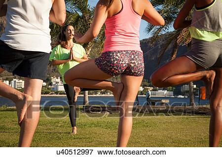 Rear view of three young women exercising with trainer in park View Large Photo Image Stock Photo - Rear view of three young women exercising with trainer in park. Fotosearch