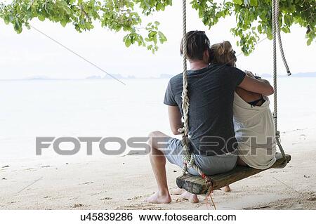 "Rear view of young couple sitting on beach swing, Kradan, Thailand" View Large Photo Image Stock Photograph - "Rear view of young couple sitting on beach swing, Kradan, Thailand". Fotosearch