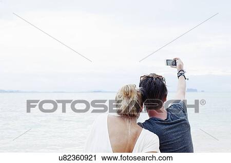 "Rear view of young couple taking smartphone selfie on beach, Kradan, Thailand" View Large Photo Image Stock Image - "Rear view of young couple taking smartphone selfie on beach, Kradan, Thailand". Fotosearch