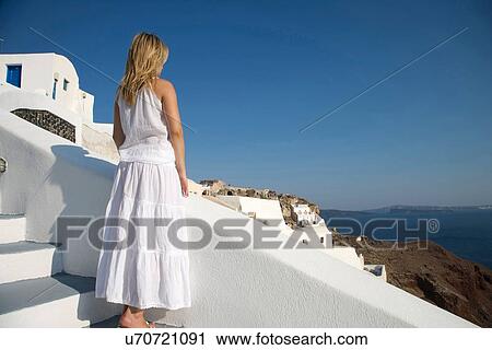 "Rear view of young female tourist looking down at sea, Oia, Santorini, Cyclades, Greece" View Large Photo Image Stock Image - "Rear view of young female tourist looking down at sea, Oia, Santorini, Cyclades, Greece". Fotosearch