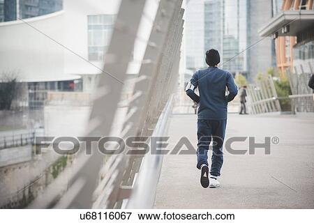 Rear view of young male runner on city footbridge View Large Photo Image Stock Photo - Rear view of young male runner on city footbridge. Fotosearch