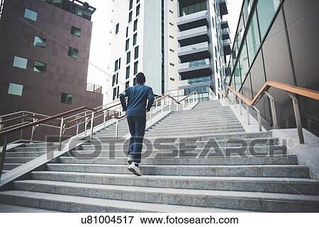 Rear view of young male runner running up city stairs View Large Photo Image Stock Photo - Rear view of young male runner running up city stairs. Fotosearch