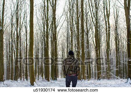 Rear view of young man standing in snow covered forest with bare trees View Large Photo Image Picture - Rear view of young man standing in snow covered forest with bare trees. Fotosearch