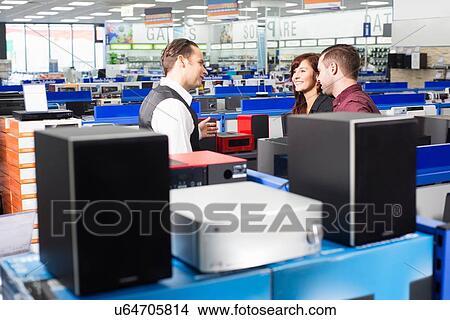 Sales assistant advising couple in electronics store View Large Photo Image Picture - Sales assistant advising couple in electronics store. Fotosearch