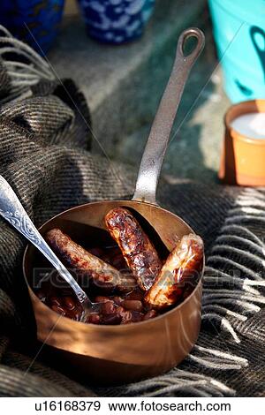 Stock Photo - Saucepan with sausages and beans on doorstep. Fotosearch