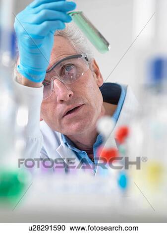 Stock Image - Scientist viewing chemical experiment in laboratory. Fotosearch