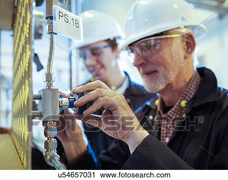 Senior and apprentice engineers adjusting pipework in power station View Large Photo Image Stock Image - Senior and apprentice engineers adjusting pipework in power station. Fotosearch