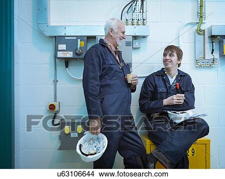 Senior and apprentice engineers talking in power station View Large Photo Image Picture - Senior and apprentice engineers talking in power station. Fotosearch