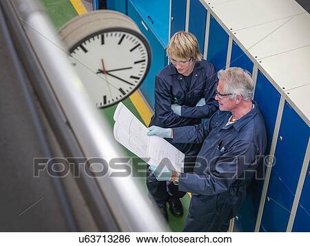 "Senior engineer instructing apprentice in factory, high angle view" View Large Photo Image Stock Photograph - "Senior engineer instructing apprentice in factory, high angle view". Fotosearch