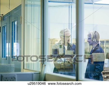 Stock Photograph - Senior engineer talking to apprentice in factory. Fotosearch