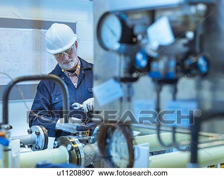 Stock Photo - Senior engineer working on pipework in power station. Fotosearch