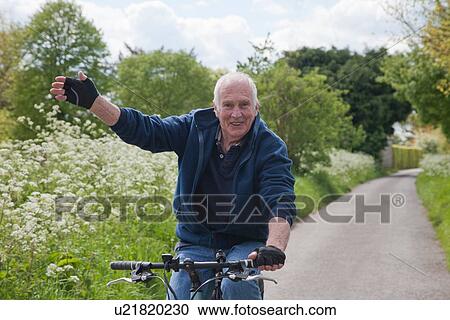 Senior man riding bike on country lane View Large Photo Image Stock Image - Senior man riding bike on country lane. Fotosearch