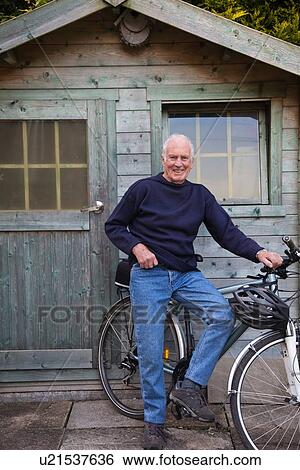 "Senior man, standing beside shed with bicycle" View Large Photo Image Stock Photograph - "Senior man, standing beside shed with bicycle". Fotosearch