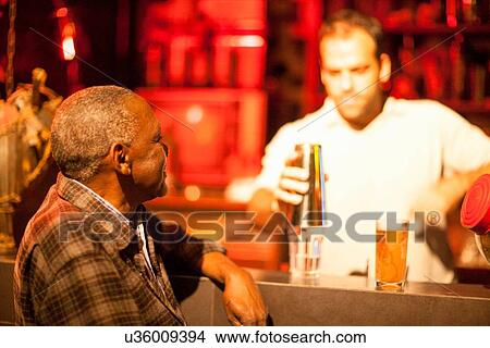 "Senior man talking to barman at cocktail bar, Rio De Janeiro, Brazil" View Large Photo Image Picture - "Senior man talking to barman at cocktail bar, Rio De Janeiro, Brazil". Fotosearch