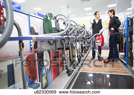 Shop assistant demonstrating vacuum cleaner in electronics store View Large Photo Image Stock Photo - Shop assistant demonstrating vacuum cleaner in electronics store. Fotosearch