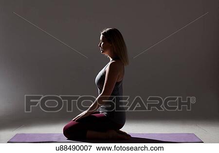 Silhouetted low key shot of young woman kneeling on mat practicing yoga View Large Photo Image Stock Photo - Silhouetted low key shot of young woman kneeling on mat practicing yoga. Fotosearch