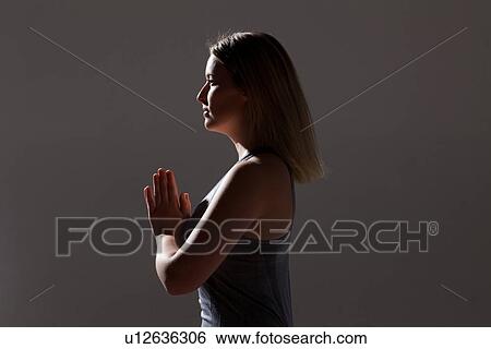 Stock Photograph - Silhouetted low key shot of young woman practicing yoga. Fotosearch