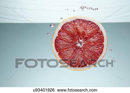 Slice of pink grapefruit underwater View Large Photo Image Stock Photograph - Slice of pink grapefruit underwater. Fotosearch
