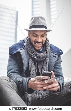 Smiling businessman sitting on stairway reading smartphone text View Large Photo Image Stock Image - Smiling businessman sitting on stairway reading smartphone text. Fotosearch