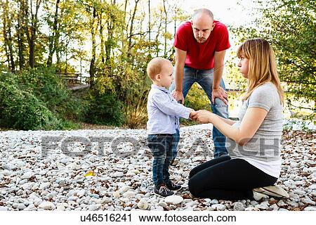 Stock Image - "Son face to face with mother, holding hands, while father looks on". Fotosearch