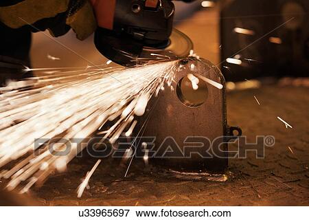 Stock Photo - Sparks from worker using grinder in factory. Fotosearch