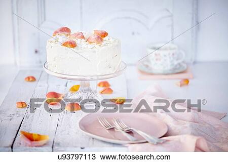 Stock Image - Still life of cream cake on cake stand garnished with rose petals. Fotosearch