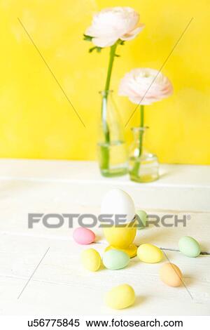Stock Photography - Still life of cut flowers in bottles and confectionery Easter eggs. Fotosearch