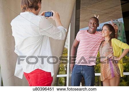 Stock Image - Student photographer taking picture of friends. Fotosearch