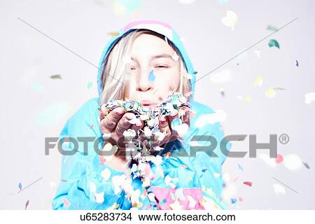 Studio portrait of young woman blowing confetti View Large Photo Image Picture - Studio portrait of young woman blowing confetti. Fotosearch