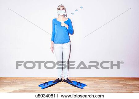 Stock Image - Studio portrait of young woman wearing flippers holding up drawing of sharks mouth. Fotosearch