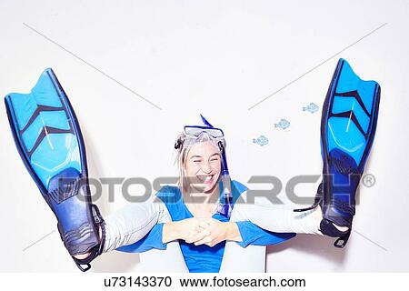 Stock Image - Studio portrait of young woman with flipper feet wearing snorkel mask. Fotosearch