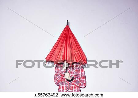 Studio shot of young woman holding red umbrella over her head View Large Photo Image Stock Image - Studio shot of young woman holding red umbrella over her head. Fotosearch