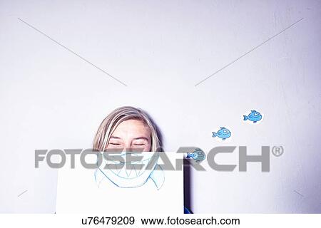 Stock Photo - Studio shot of young woman holding up drawing of sharks mouth. Fotosearch