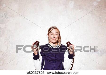 Stock Photography - Studio shot of young woman holding up chocolate marshmallows. Fotosearch