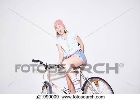 Studio shot of young woman laughing whilst sitting on bicycle View Large Photo Image Stock Photo - Studio shot of young woman laughing whilst sitting on bicycle. Fotosearch