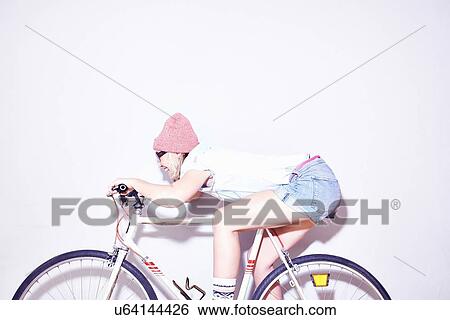 Studio shot of young woman leaning forward on bicycle View Large Photo Image Stock Photograph - Studio shot of young woman leaning forward on bicycle. Fotosearch