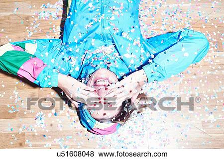 Studio shot of young woman lying on floor covered in confetti View Large Photo Image Stock Photo - Studio shot of young woman lying on floor covered in confetti. Fotosearch