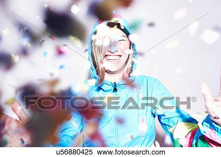 Stock Photography - Studio shot of young woman scattering confetti. Fotosearch