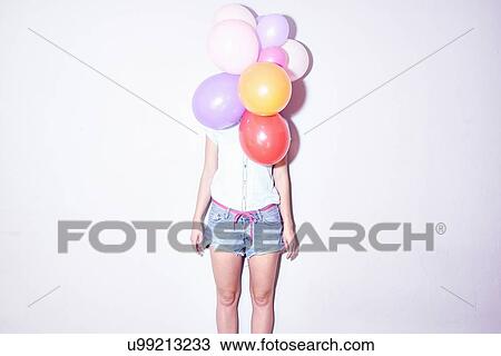 Studio shot of young woman standing behind bunch of balloons View Large Photo Image Stock Image - Studio shot of young woman standing behind bunch of balloons. Fotosearch