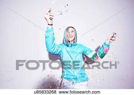 Studio shot of young woman throwing confetti View Large Photo Image Stock Photo - Studio shot of young woman throwing confetti. Fotosearch