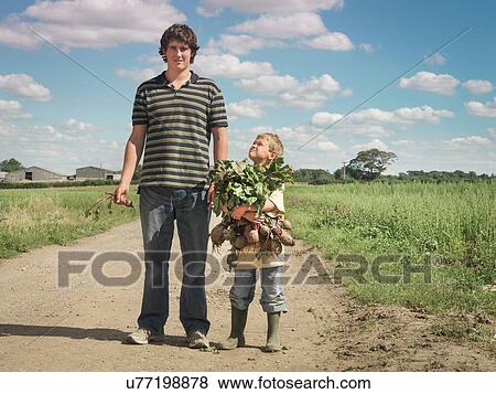 Stock Photo - Tall and smaller farmers sons carrying armful of organic beetroot. Fotosearch