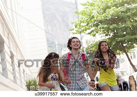 "Three adult friends running and holding hands on street, Copacabana town, Rio De Janeiro, Brazil" View Large Photo Image Stock Photo - "Three adult friends running and holding hands on street, Copacabana town, Rio De Janeiro, Brazil". Fotosearch