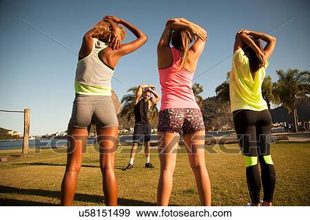 Stock Photo - "Three female friends exercising in park with personal trainer, Rio De Janeiro, Brazil". Fotosearch