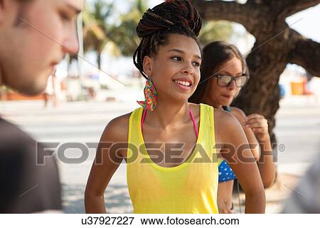 Stock Photo - "Three young adult friends chatting on sidewalk, Copacabana, Rio De Janeiro, Brazil". Fotosearch