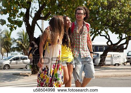 Stock Photo - "Three young adult friends strolling on sidewalk, Copacabana, Rio De Janeiro, Brazil". Fotosearch