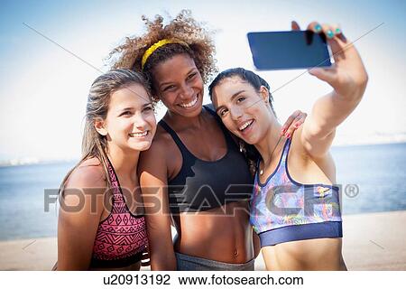 Three young women photographing themselves with phone View Large Photo Image Stock Image - Three young women photographing themselves with phone. Fotosearch