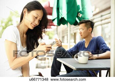 Stock Photo - "Tourist couple at sidewalk cafe using smartphones, The Bund, Shanghai, China". Fotosearch
