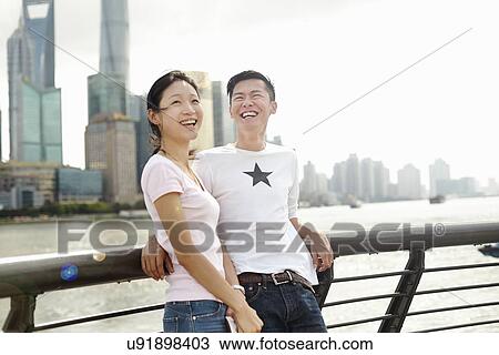Stock Image - "Tourist couple leaning against bridge railing, The Bund, Shanghai, China". Fotosearch