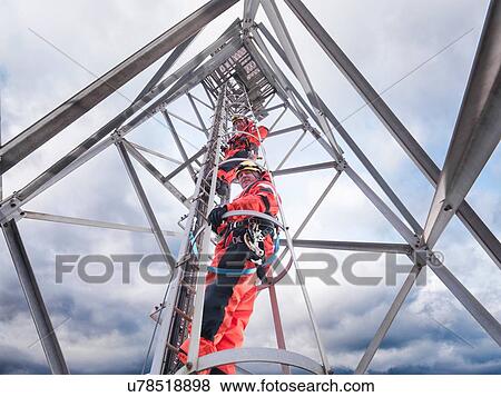 Stock Photo - "Tower workers climbing radio tower on offshore windfarm, low angle view". Fotosearch