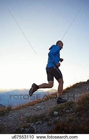 Stock Image - "Trail runner running uphill, Valais, Switzerland". Fotosearch